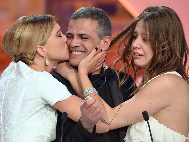 A atriz Lea Seydoux beija o diretor franco-tunisiano Abdellatif Kechiche, ao lado da atriz Adele Exarchopoulos, após o anúncio de que o filme protagonizado por ela e dirigido pelo cineasta ganhou a Palma de Ouro em Cannes (Foto: Alberto Pizzoli / AFP)