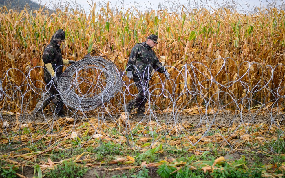 Imagem de 2015 mostra soldados húngaros com cerca de arame farpado para impedir passagem de imigrantes na fronteira com a Eslovênia — Foto:  Jure Makovec/AFP