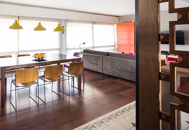 A sala de jantar tem pendentes amarelos no estilo retrô e cadeiras roxas, diferentes da composição, em cada ponta da mesa (Foto: Marcelo Donadussi/Fotografia de Arquitetura)