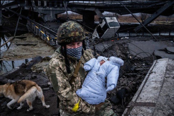 Bebê é carregado por soldado, em meio a escombros (Foto: Reprodução/The Sun)