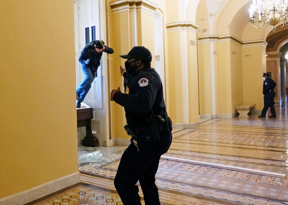 Policial do Capitólio espirra spray de pimenta em apoiador de Trump que invadiu o prédio do Congresso americano, nesta quarta-feira (6), em Washington — Foto: Kevin Dietsch/pool via Reuters