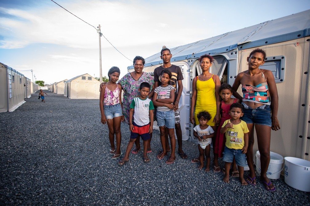 Juleima e parte da família posam para foto diante da cabana onde foram abrigados pela Operação Acolhida, à espera do processo de interiorização — Foto: Fábio Tito/g1