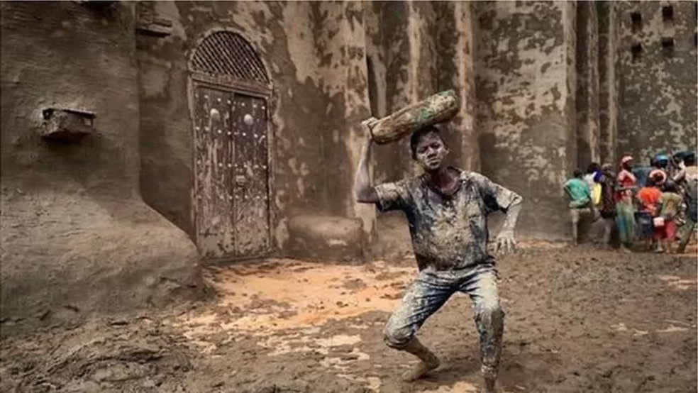 Todos os anos, os moradores de Djenné, no Máli, reúnem-se para reparar e recobrir com argila a Grande Mesquita - a maior construção de barro do mundo — Foto: GETTY