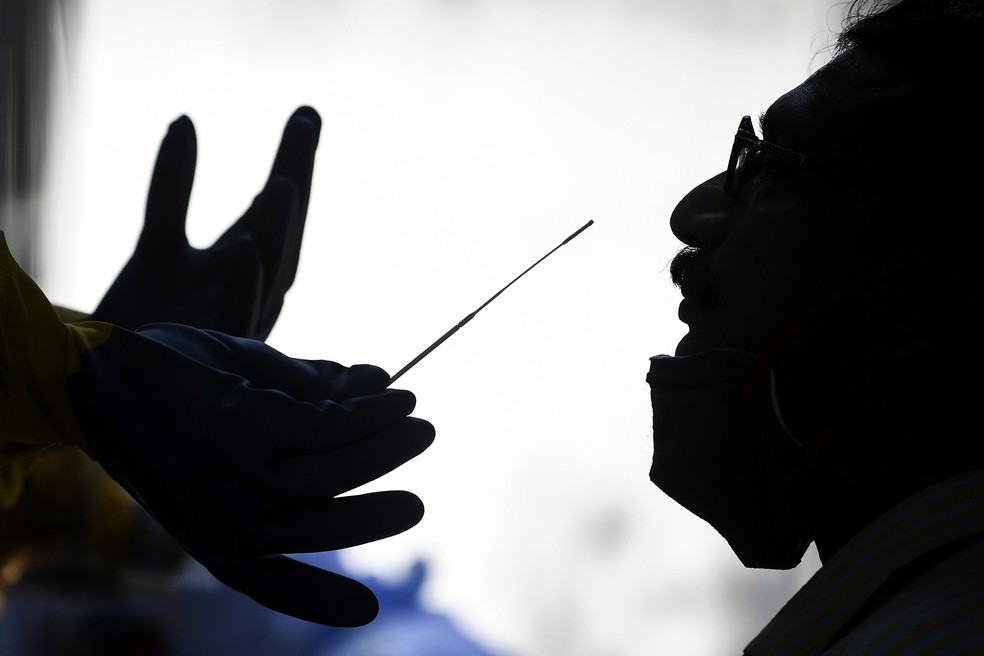 30 de abril - Agente de saúde usa cotonete para coletar amostra de um homem para testar presença do coronavírus (COVID-19).  — Foto: Sajjad Hussain/AFP