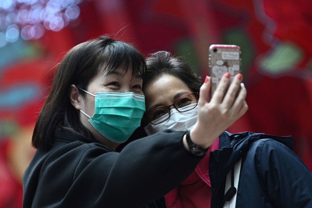Mulheres com máscaras faciais tiram uma selfie em Hong Kong, nesta quarta-feira (5) — Foto: Anthony Wallace / AFP