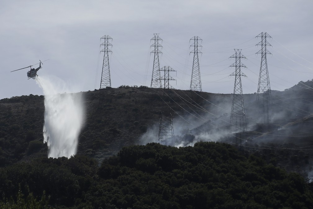 Helicóptero joga água nas chamas nas montanhas de San Bruno, na Califórnia, na quinta-feira (10). — Foto: Jeff Chiu/AP