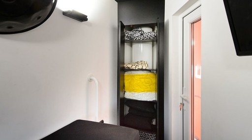 Na outra parede do quarto está um pequeno guarda-roupas. Ao lado, um corredor dá acesso à escada que vai até o terraço.