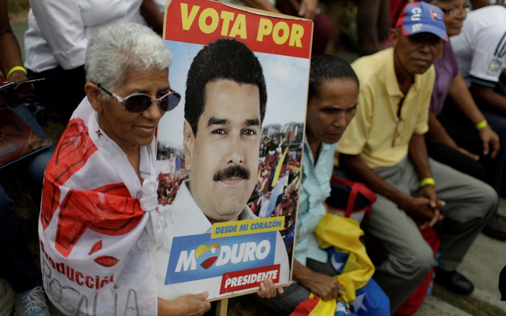Eleitora de Nicolás Maduro exibe cartaz do presidente venezuelano em Caracas (Foto: Reuters/Marco Bello)