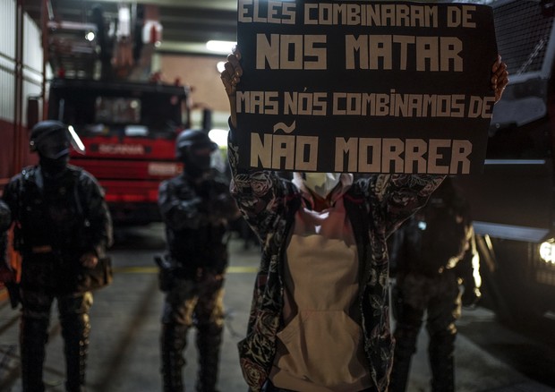 A demonstrator holds up a sign that reads &quot;They agreed to kill us but we agreed not to die in front of a battalion of the Military Fire Brigade during protest against racism, police violence and the operation that took place in the Jacarezinho favela (Foto: NurPhoto via Getty Images)