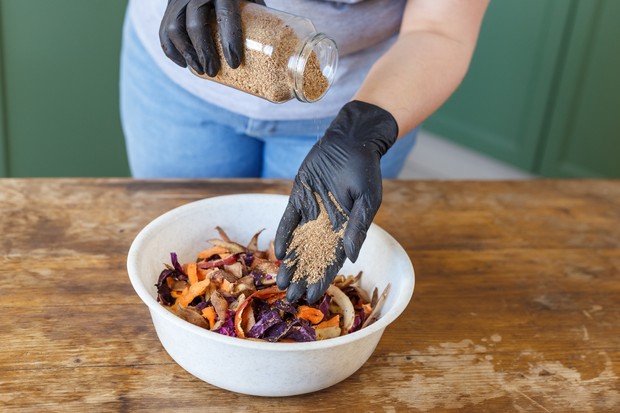 Woman puts bokashi into the pile of kitchen fruits and vegetable scraps for compost recycling (Foto: Getty Images/iStockphoto)