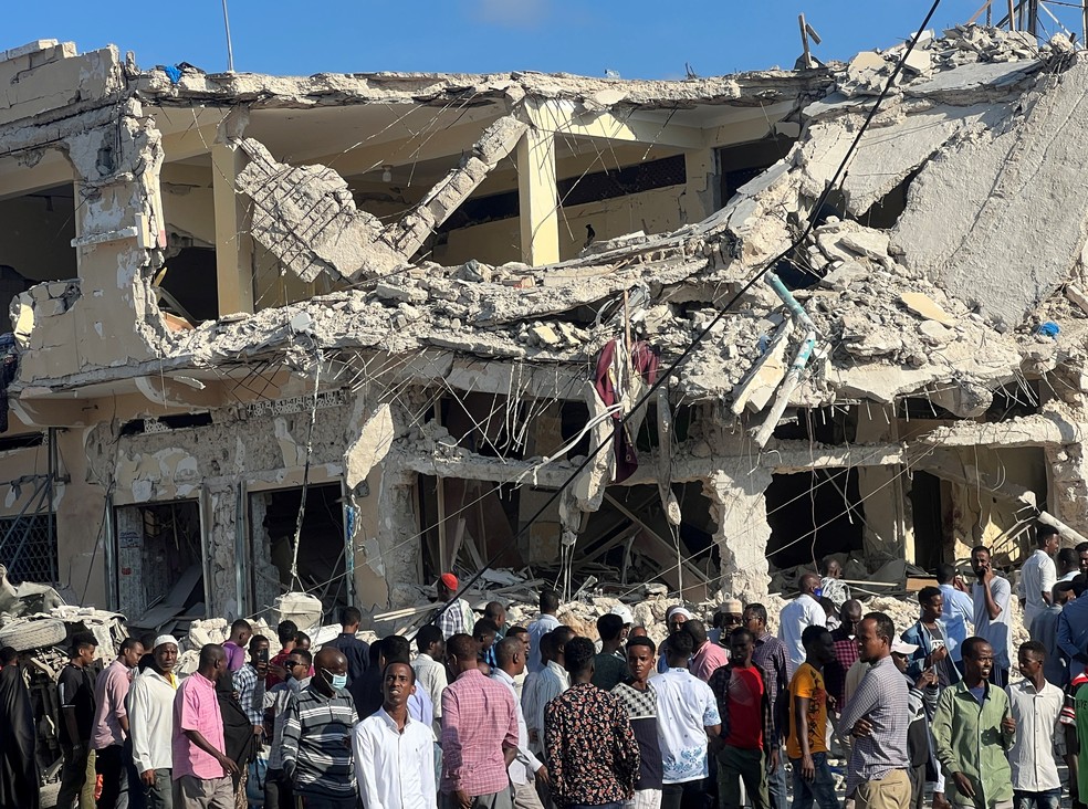 Civis se reúnem perto das ruínas de um prédio no local de uma explosão em Mogadíscio, na Somália, em 30 de outubro de 2022 — Foto: REUTERS/Abdirahman Hussein