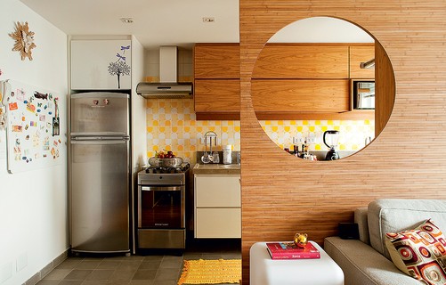 O painel de bambu reserva a cozinha sem ocultá-la no apartamento de 43 m² da arquiteta Fernanda Milani. Os móveis planejados têm nichos para eletrodomésticos 