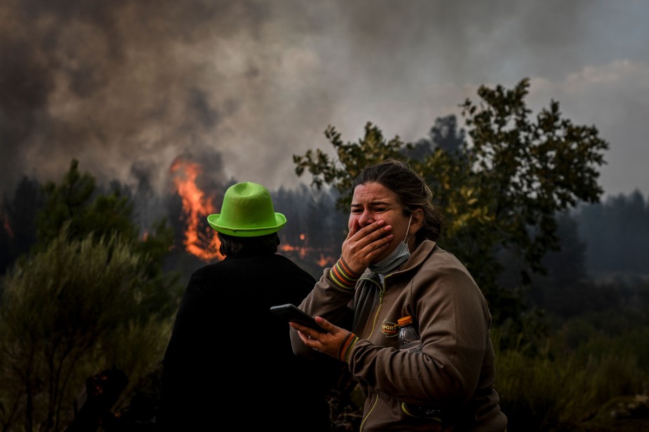 Mulher reage ao avanço do incêndio em área rural de Covilhã, em Portugal, este ano