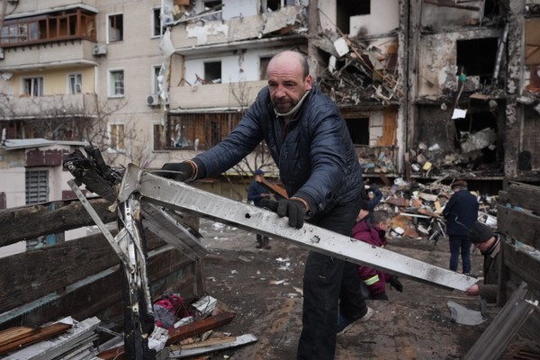 Um homem remove entulhos de um prédio ucraniano bombardeado pelo exército russo (Foto: Getty Images)