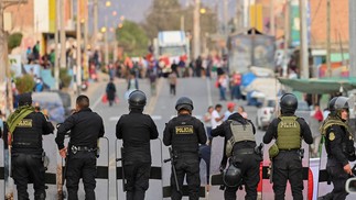 Policiais montam guarda em uma rua de Humay, Peru, depois de deter um comboio de manifestantes Chancas, da região central dos Andes, a caminho de Lima para participar de uma grande protesto contra a presidente Dina Boluarte — Foto: Cris BOURONCLE / AFP