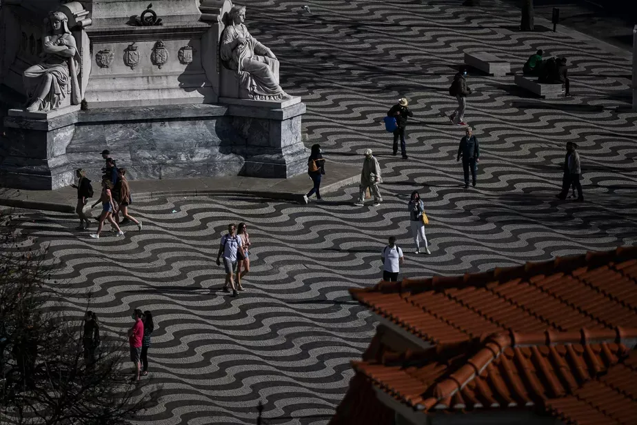 Pedestres caminham na Praça do Rossio, em Lisboa