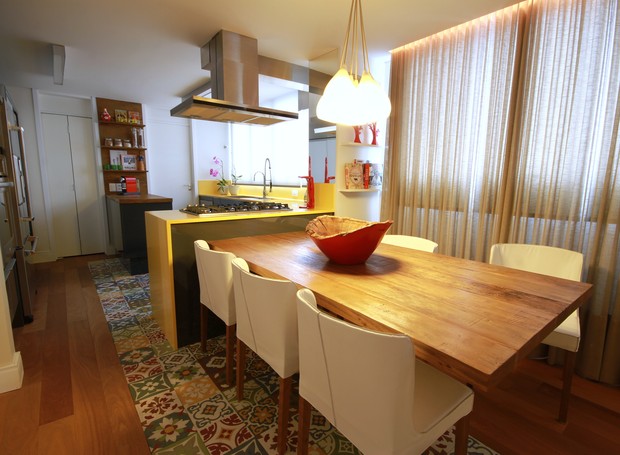 A sala de jantar foi integrada à cozinha com mesa de madeira de demolição, da Aroeira, e cadeiras orquídea de couro branco, da Dpot (Foto: Mário Bock/Divulgação)
