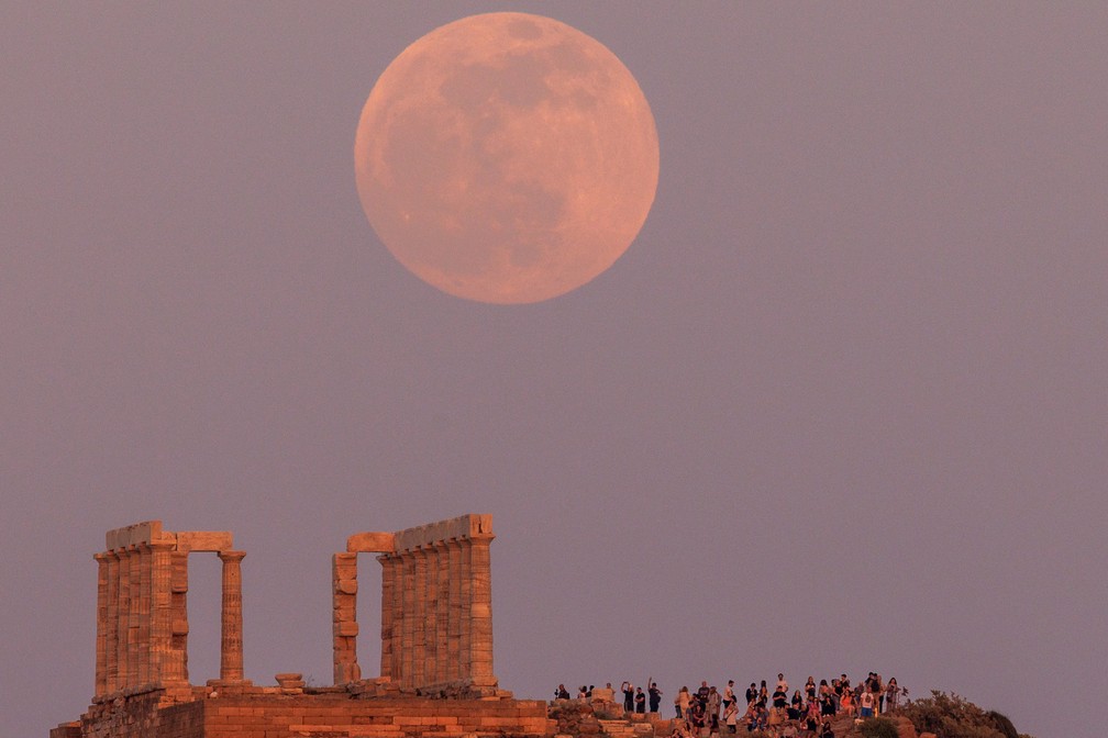 Grécia: pessoas observam a lua cheia nascendo atrás do Templo de Poseidon, perto de Atenas neste domingo, 15 — Foto: Alkis Konstantinidis/Reuters