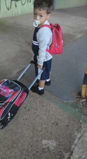 Olha o Isaac, de 2 anos, com mochila de rodinha e lancheira nas costas
