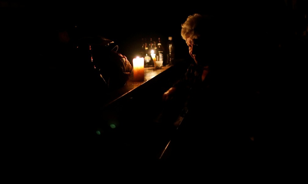 Mulher usa a luz de velas enquanto trabalha em um bar durante um blecaute na Venezuela — Foto: Carlos Garcia Rawlins/Reuters