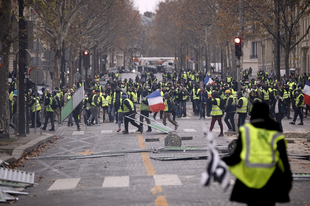 Manifestantes de coletes amarelos protestam contra o aumento de impostos do governo Macron neste sábado (1) na avenida Champs-Elysées, em Paris. — Foto: Kamil Zihnioglu/AP