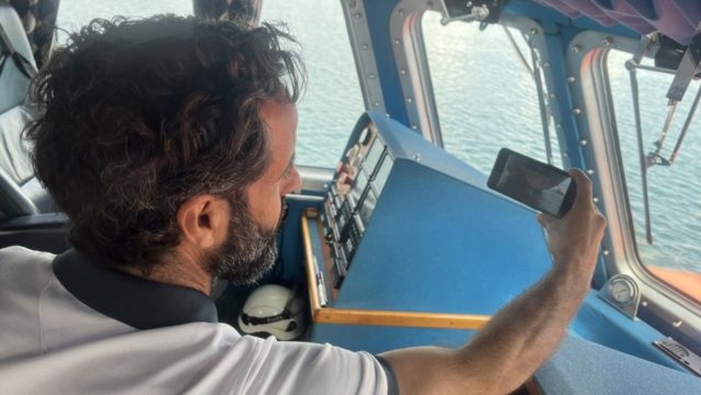 O capitão do navio no qual viajaram os imgirantes, Orlando Ramos Alayón, fotografa o trio.  — Foto: Salvamento Marítimo de España via BBC