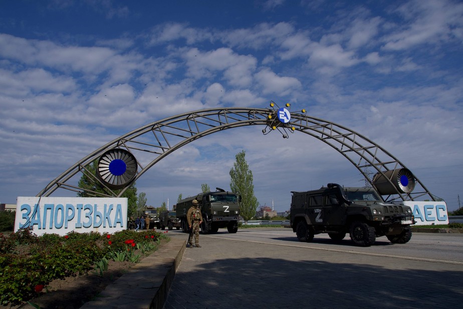 Caminhões russos passam pelo portão de entrada da central nuclear de Zaporíjia, na cidade ucraniana de Enerhodar