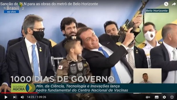 Bolsonaro chamou criança fardada e com réplica de arma para sentar ao seu lado em evento em Belo Horizonte (Foto: Reprodução TV Brasil via BBC News)