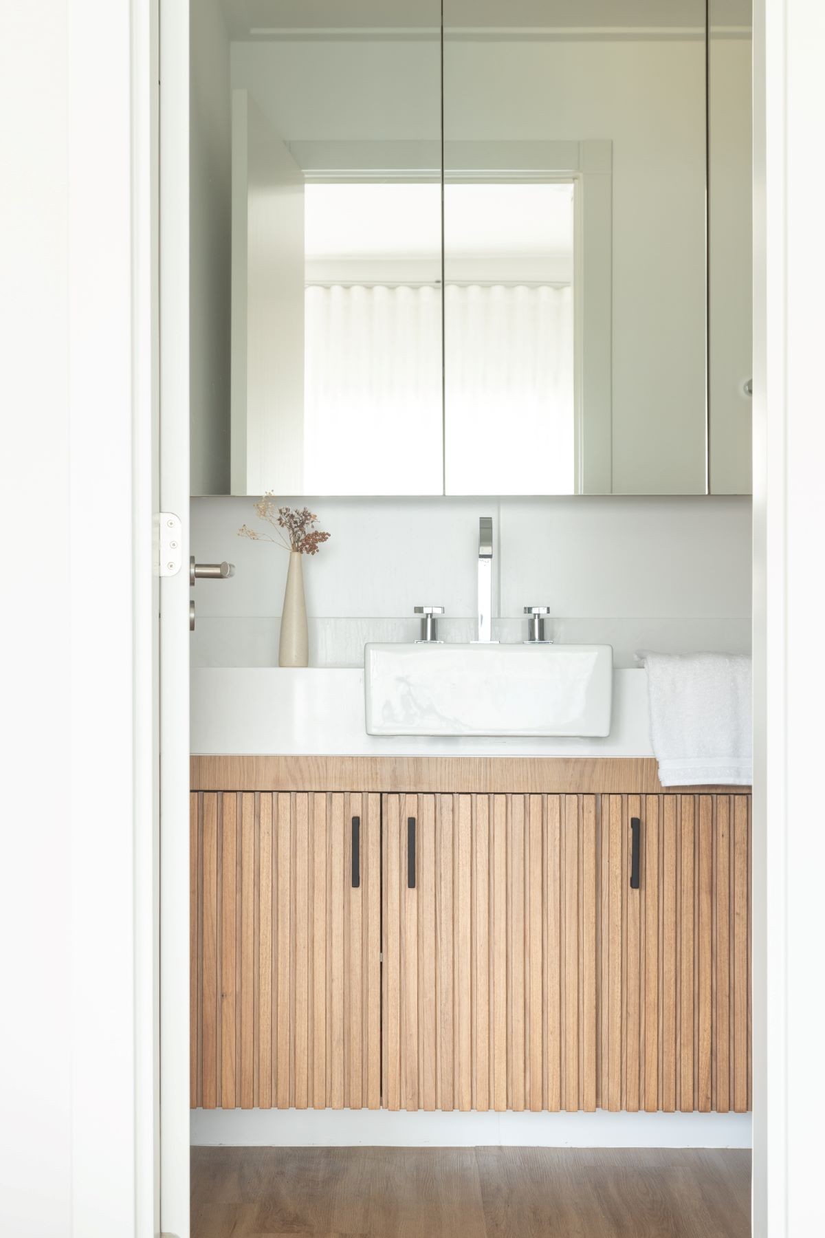 BATHROOM |  In the bathroom, the slatted furniture in natural wood composes with the rest of the apartment (Photo: Mariana Boro / A CASAA / Publicity )