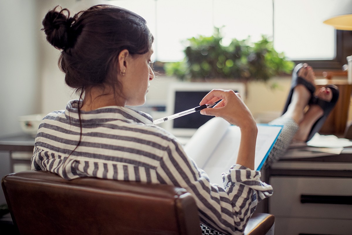 Businesswoman reading paperwork with feet up on desk (Foto: Getty Images/Caiaimage)