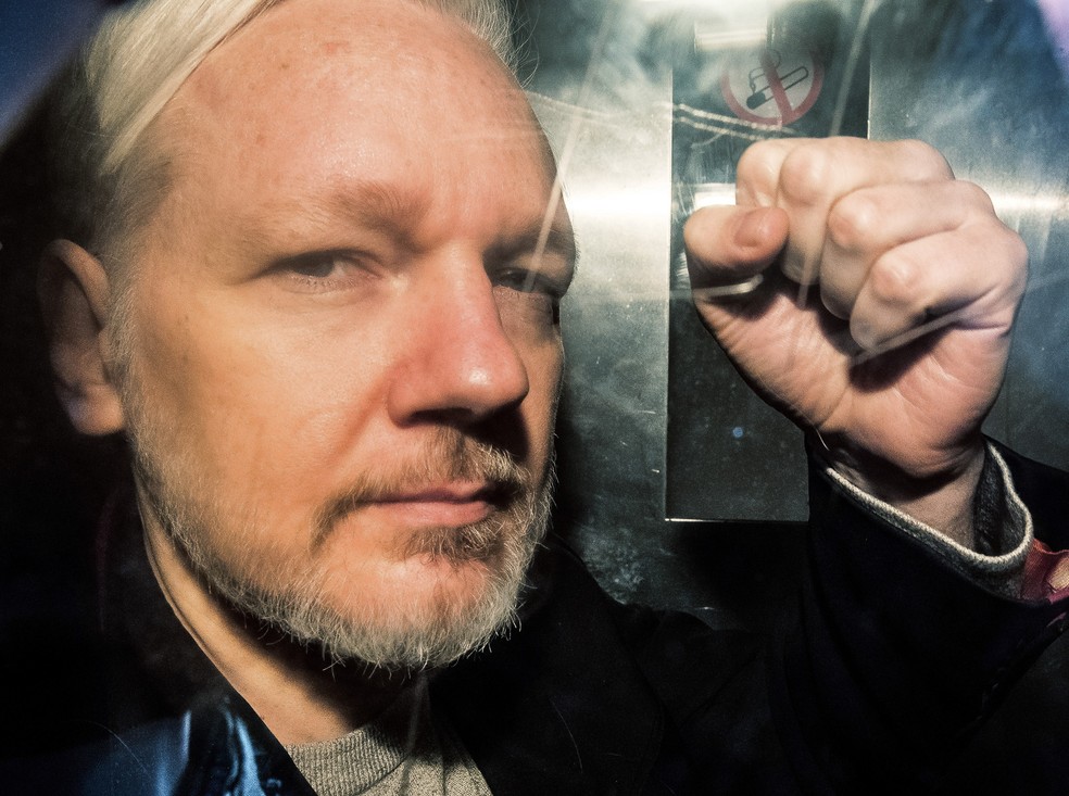 O fundador do Wikileaks, Julian Assange, mostra o punho em riste dentro de uma van em 1º de maio de 2020, ao chegar a tribunal em Londres — Foto: Daniel Leal-Olivas/AFP