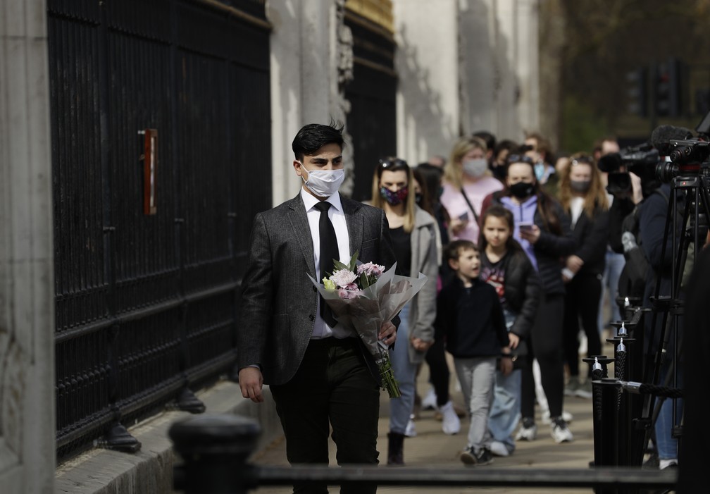 Pessoas fazem fila para deixar flores e ver o anúncio da morte do príncipe Philip em frente ao portão do Palácio de Buckingham, em Londres, em 9 de abril de 2021 — Foto: Matt Dunham/AP