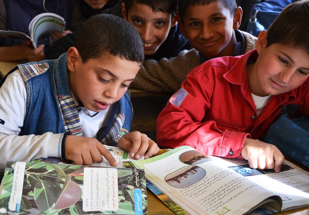 Imagem de dezembro de 2017 mostra crianças iraquianas lendo livro em escola de Mossul (Foto: Ahmad Muwafaq/AFP)