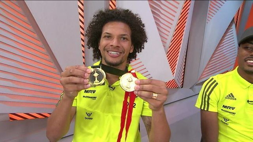 Arão mostra medalhas das Libertadores de 2012, pelo Corinthians, e 2019, pelo Flamengo — Foto: Reprodução / TV Globo