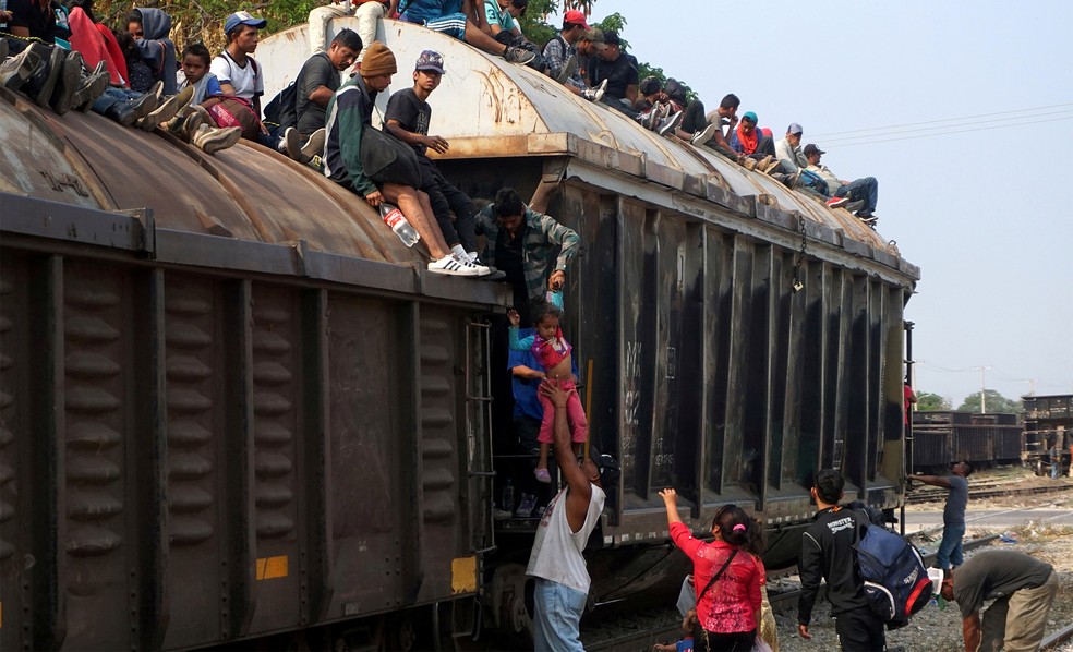 Migrantes centro-americanos sobem uma criança para o teto de vagões de um trem conhecido como 'A Besta', em Ixtepec, no México, na rota que tem os EUA como destino — Foto: Jose de Jesus Cortes/Reuters