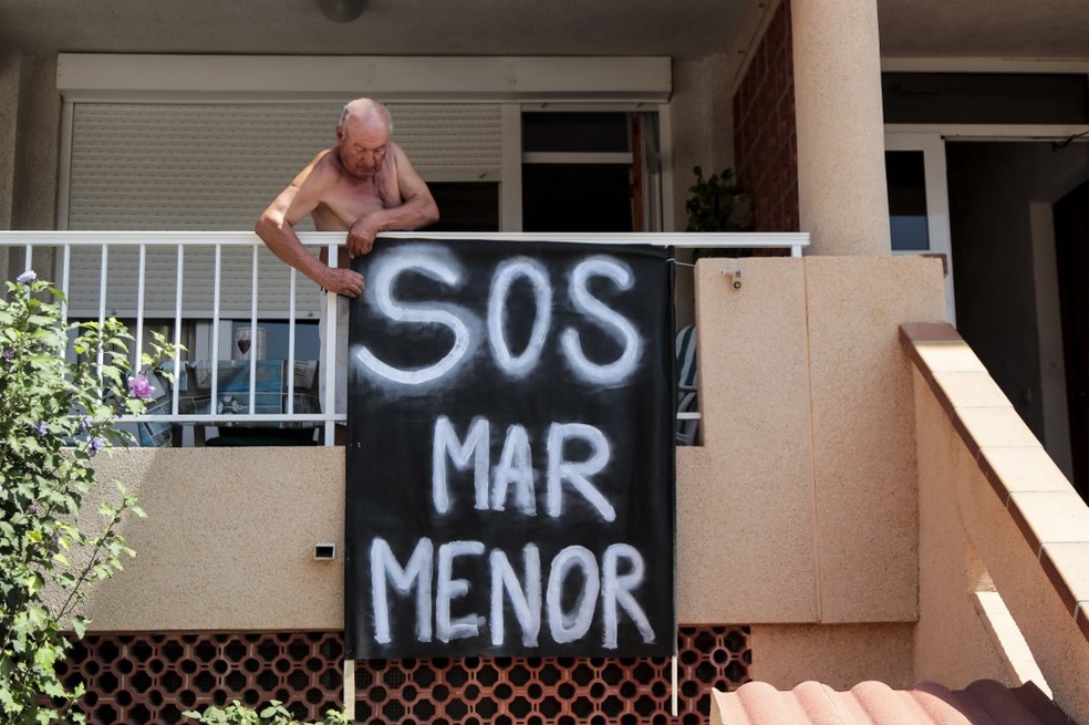 Foto de 25 de agosto de 2021 mostra homem pendurando faixa contra a poluição na laguna Mar Menor, na Espanha de onde foram retiradas toneladas de peixes que morreram por causa de poluentes agrícolas — Foto: Jose Miguel Fernandez/AFP