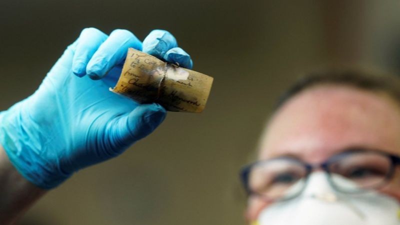 Integrante da equipe de preservação do Departamento de Recursos Históricos da Virgínia manuseia item da 'cápsula do tempo' (Foto: Reuters via BBC News)