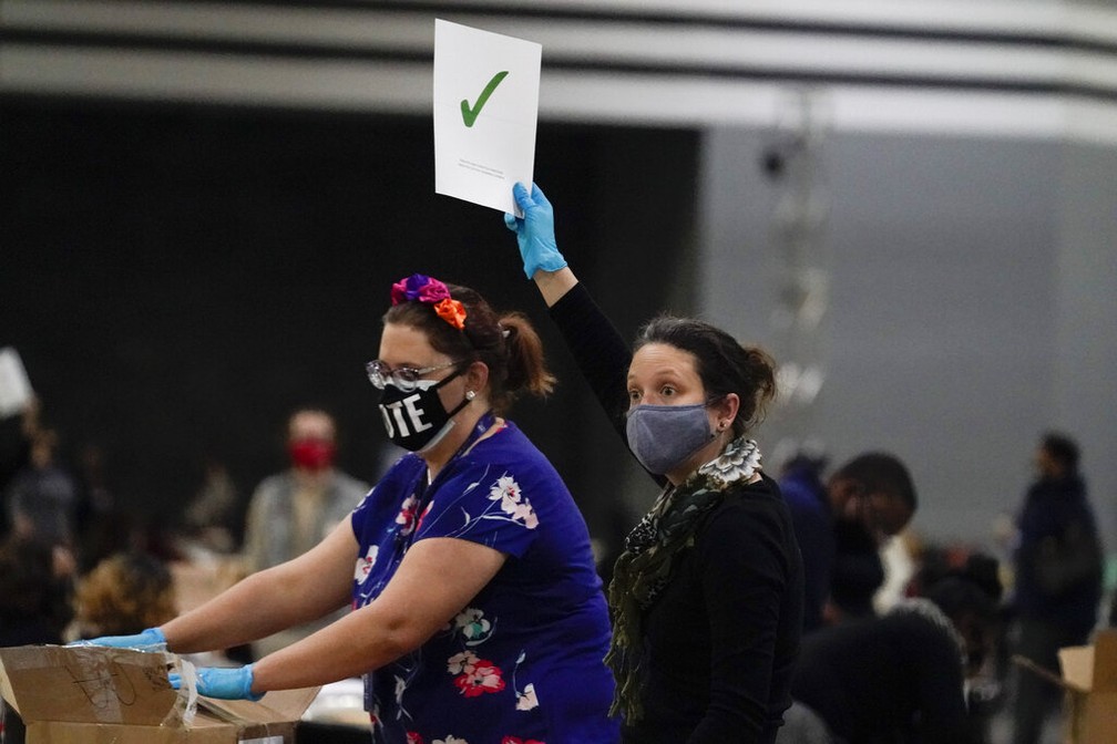 Funcionária do serviço de contagem de votos levanta placa que indica apuração completa em um dos pacotes de cédulas em Atlanta, na Geórgia (EUA), no sábado (14) — Foto: Brynn Anderson/AP Photo