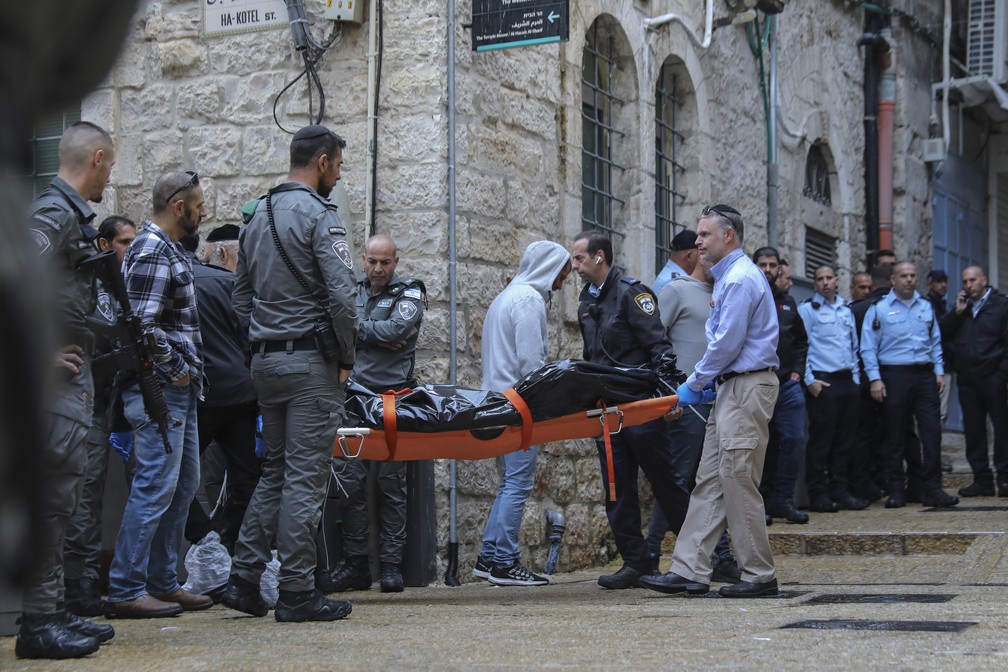 Forças de segurança israelenses e profissionais de saúde carregam o corpo de um palestino que foi morto a tiros pela polícia após matar um israelense e ferir outros quatro em um ataque a tiros na Cidade Velha de Jerusalém, em Israel, em 21 de novembro de 2021 — Foto: Mahmoud Illean/AP