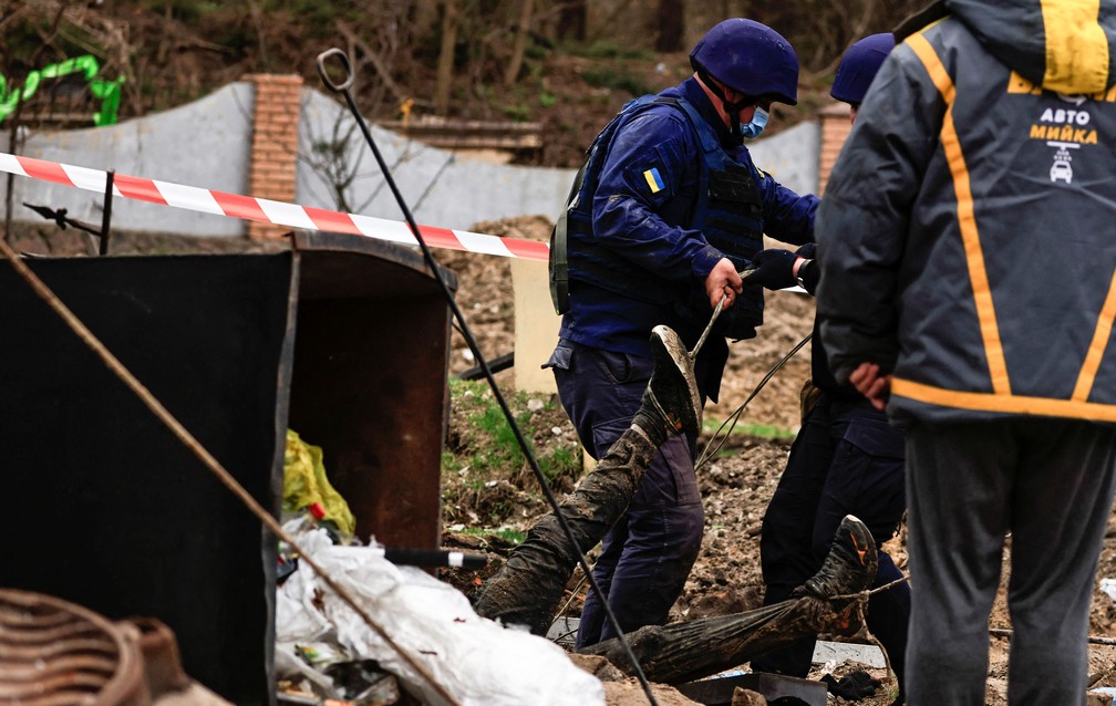 Polícia retira corpos de um poço num posto de gasolina em Buzova, na região de Kiev, neste domingo (10)