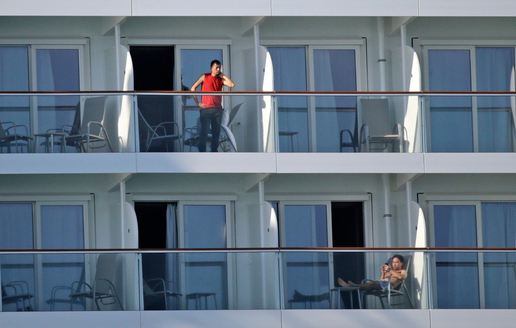 Tripulantes são vistos em suas varandas no navio Norwegian Encore, no porto de Miami, nos EUA, em 26 de março — Foto:  David Santiago/Miami Herald via AP