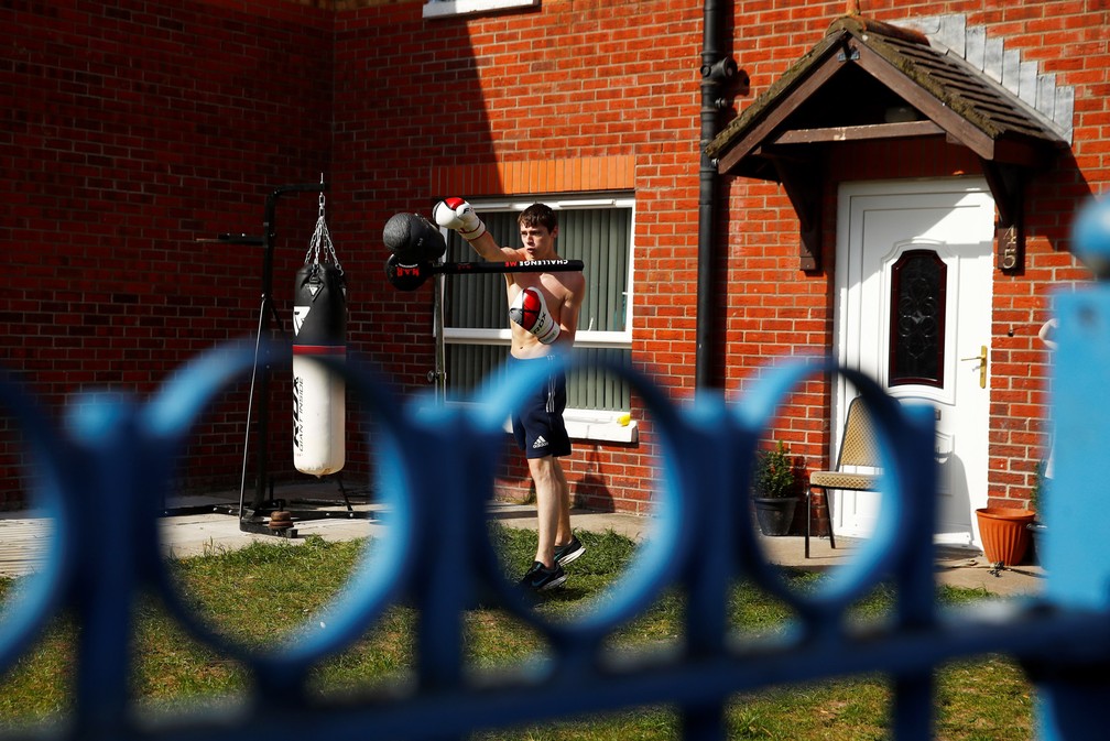 Gerard se exercita com equipamentos de boxe no quintal de sua casa durante isolamento para evitar a disseminação da doença de coronavírus (COVID-19) em Belfast, Irlanda do Norte — Foto: Jason Cairnduff/Reuters