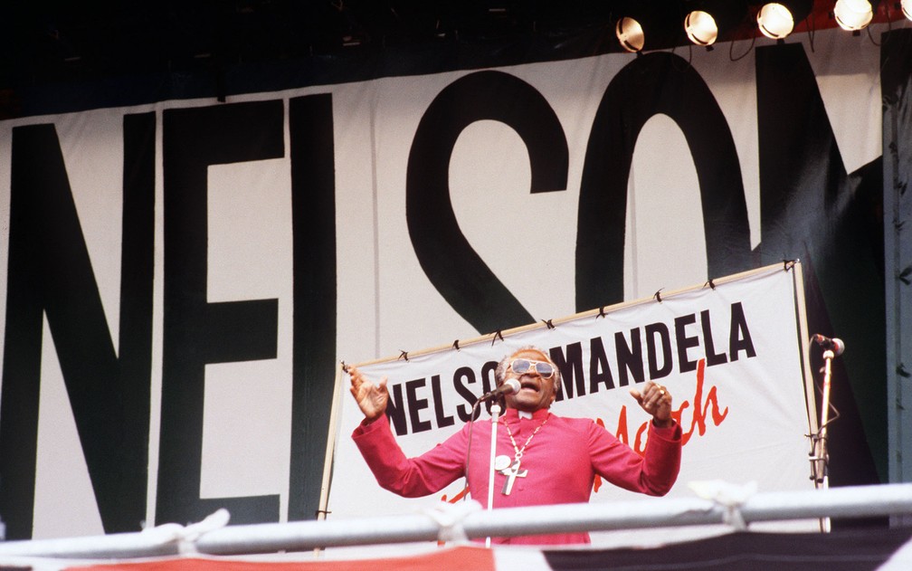 Julho de 1988 - O arcebispo Desmond Tutu fala para multidão em evento de protesto pedindo a libertação de Mandela, no Hyde Park, em Londres. O ato ocorreu no dia 17, à véspera do aniversário de 70 anos do líder então encarcerado — Foto: Anna Tully/AFP/Arquivo