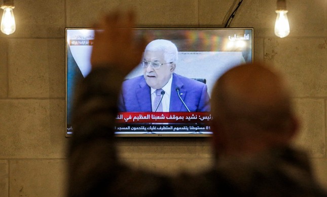 Homem vê Mahmoud Abbas falar na televisão na Cisjordânia