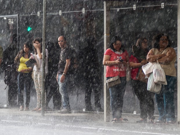 Pedestres se protegem de temporal nos arredores da estação São Bento do Metrô, na região central de São Paulo, nesta sexta-feira (07) (Foto: Dario Oliveira/Estadão Conteúdo)