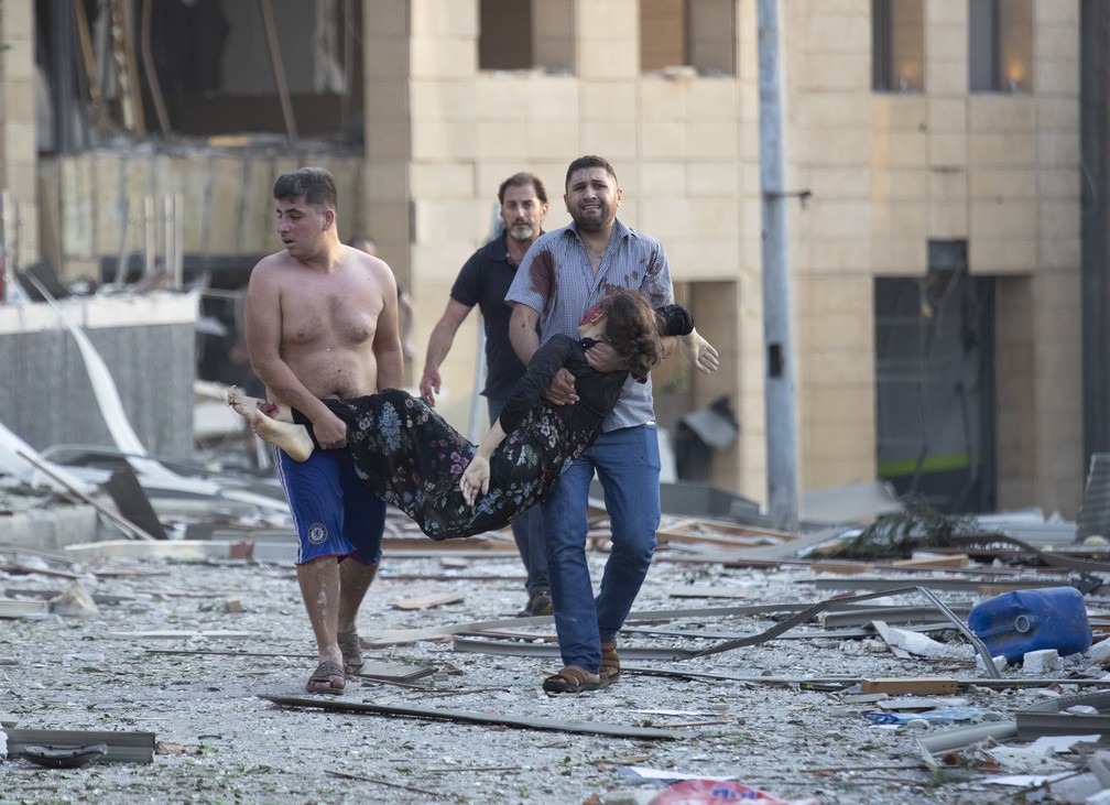 Homens carregam ferido em explosão em Beirute — Foto: Hussein Malla/AP