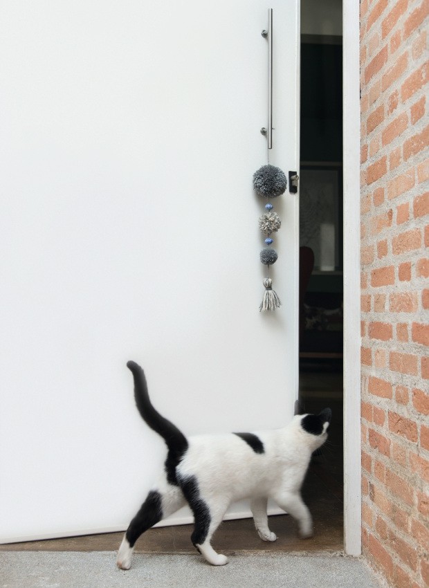 Triunfante. Não é só o gato que fica curioso para espiar: pompons coloridos, amarrados na maçaneta, são um belo passaporte de entrada (Foto: Cacá Bratke / Editora Globo)