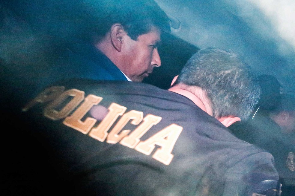 O presidente deposto do Peru, Pedro Castillo, é escoltado ao ser transferido para uma base da polícia — Foto: Renato Pajuelo / AP Photo