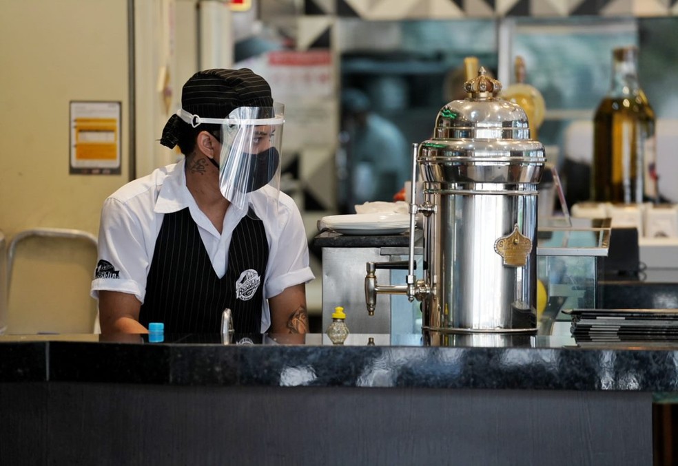 Funcionária de restaurante usa máscara e protetor facial — Foto: Marcelo Brandt/G1