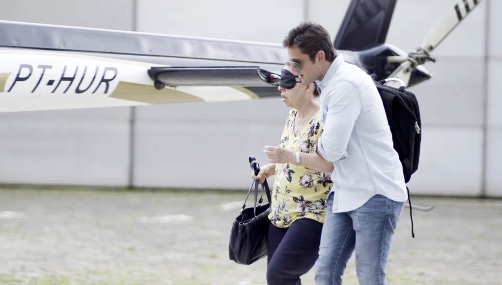 Renzo (Rafael Cardoso) leva Lúcia (Cristina Pereira) vendada até o helicóptero em 'Salve-se Quem Puder' — Foto: Globo